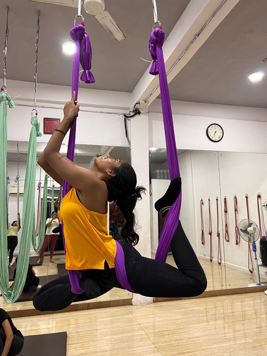 Aerial hammock pose on purple silks