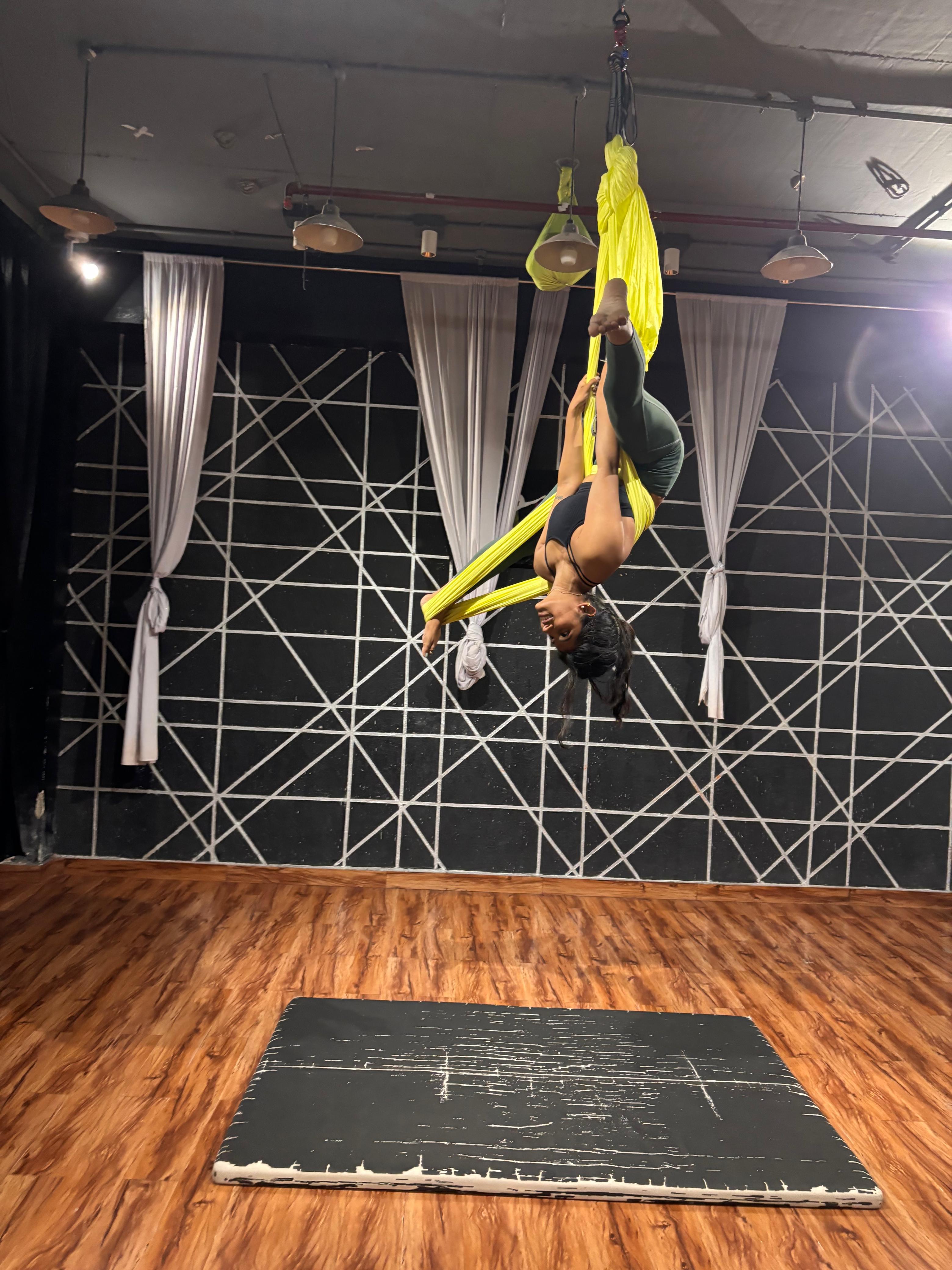 Inverted aerial pose on yellow silks